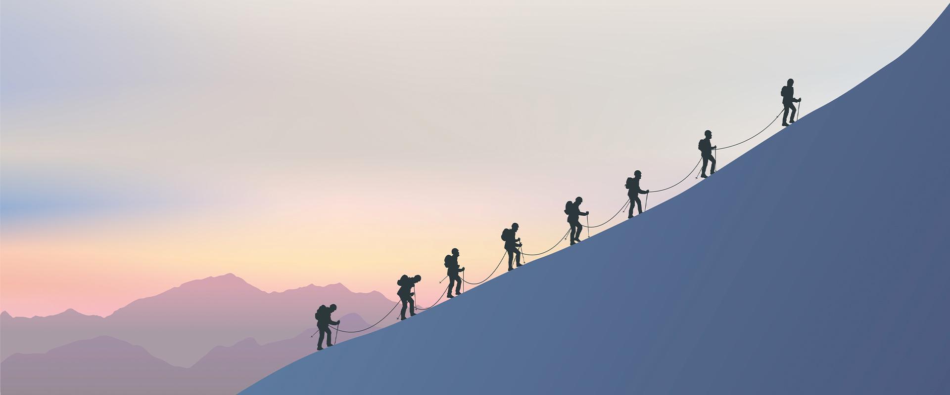 Silhouettes of people climbing a mountain